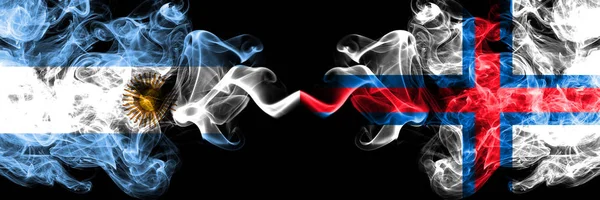 Argentina vs Ilhas Faroé bandeiras de fogo místico fumegantes colocadas lado a lado. Conceito de bandeiras de fumaça abstrata sedosa de cor grossa — Fotografia de Stock