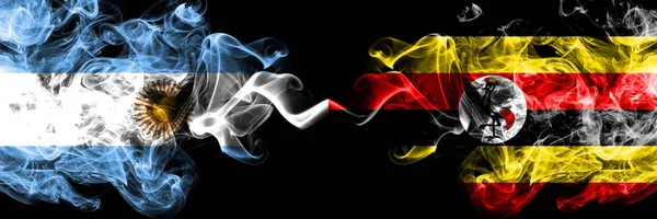 Argentina vs Uganda, Ugandas rökiga mystiska brandflaggor placerade sida vid sida. Tjock färgad silkeslen abstrakt rök flaggor koncept — Stockfoto