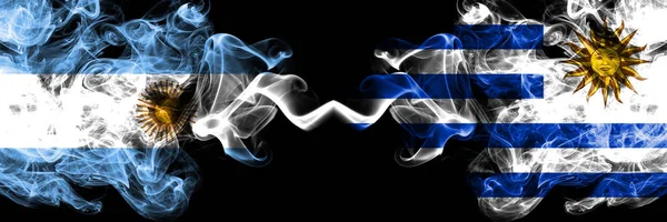 Αργεντινή εναντίον Ουρουγουάης, Ουρουγουανός καπνιστή μυστικιστική σημαίες φωτιά τοποθετούνται δίπλα-δίπλα. Χοντρό χρώμα μεταξένια αφηρημένη έννοια σημαίες καπνού — Φωτογραφία Αρχείου