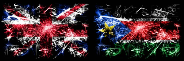 Storbritannien, Storbritannien vs Sydsudan Nyårsfirande resa gnistrande fyrverkerier flaggor koncept bakgrund. Kombination av två abstrakta staters flaggor. — Stockfoto