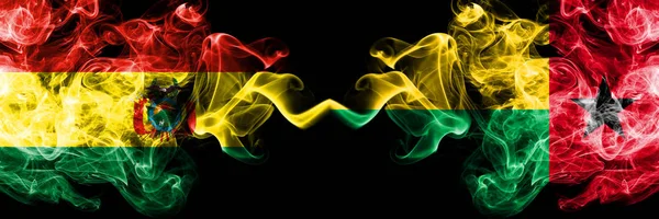 Bolivien, Bolivien vs Guinea Bissau rauchige mystische Staaten Flaggen nebeneinander platziert. Konzept und Idee dicke farbige seidig abstrakte Rauchfahnen — Stockfoto