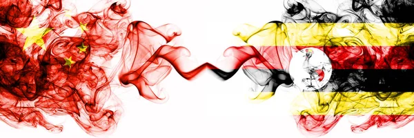 Banderas de China, China vs Uganda, estados místicos humeantes ugandeses colocadas una al lado de la otra. Banderas de humo abstractas sedosas de color grueso concepto e idea — Foto de Stock