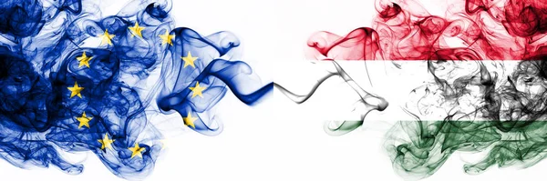 Eu, Ευρωπαϊκή Ένωση εναντίον Ουγγαρίας, ουγγρικές καπνισμένες μυστικιστικές σημαίες τοποθετημένες δίπλα-δίπλα. Πυκνό χρώμα μεταξένια αφηρημένες σημαίες καπνού συνδυασμό — Φωτογραφία Αρχείου