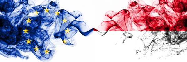 Eu, Europese Unie vs Monaco, Monacan rokerige mystieke vlaggen naast elkaar geplaatst. Dikke gekleurde zijdeachtige abstracte rookvlaggen combinatie — Stockfoto