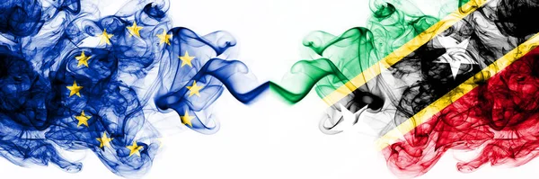 Europa, Europeiska unionen mot Saint Kitts och Nevis rökiga mystiska flaggor placerade sida vid sida. Tjock färgad silkeslen abstrakt rök flaggor kombination — Stockfoto