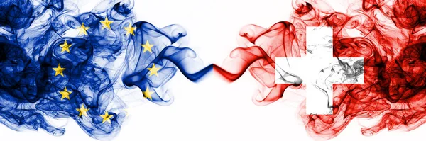 UE, Unión Europea vs Suiza, Banderas místicas ahumadas suizas colocadas una al lado de la otra. Combinación de banderas de humo abstractas sedosas de color grueso — Foto de Stock