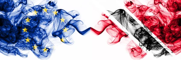 Eu, Europese Unie vs Trinidad en Tobago rokerige mystieke vlaggen naast elkaar geplaatst. Dikke gekleurde zijdeachtige abstracte rookvlaggen combinatie — Stockfoto