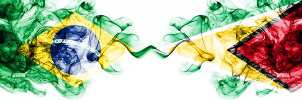 Brazylia, Brazylijczyk vs Gujana, Gujany dymiące mistyczne flagi umieszczone obok siebie. Grube kolorowe jedwabiste abstrakcyjne połączenie flag dymu — Zdjęcie stockowe
