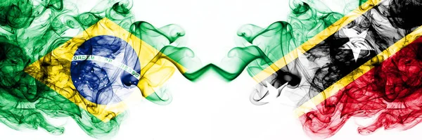 Brazylia, Brazylia vs Saint Kitts i Nevis smoky mistyczne flagi umieszczone obok siebie. Grube kolorowe jedwabiste abstrakcyjne połączenie flag dymu — Zdjęcie stockowe