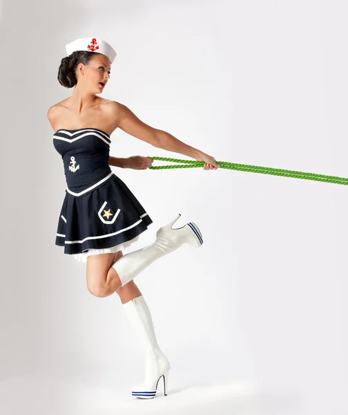 Красавица в матросском костюме тянет за верёвку — стоковое фото