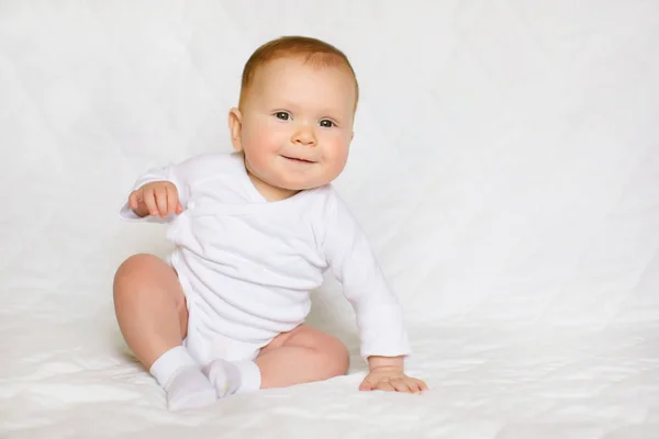 Porträtt av skönheten. Liten söt baby flicka i vit Sparkdräkt i sovrum Royaltyfria Stockbilder