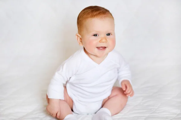 Retrato de adorabilidad. Niña linda en blanco mameluco en el dormitorio Imagen De Stock