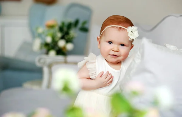 Portréja egy aranyos mosolygós kislány otthon-könnyű belső fehér ruhát. — Stock Fotó
