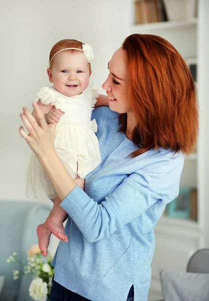 O femeie drăguţă ţinând în braţe un nou-născut zâmbitor. Mama și daugthter — Fotografie, imagine de stoc