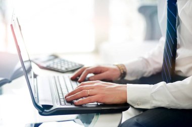 Fotoğraf üzerinde modern ofis çalışma iş adamı. Cam masa oturma ve çağdaş defter, manifatura mesaj klavye kullanarak adam. Yatay, film, parlama efekti