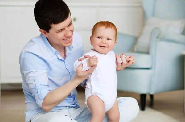 Padre y pequeño Dauther. Bebé dando los primeros pasos con la ayuda del padre en el interior del hogar — Foto de Stock