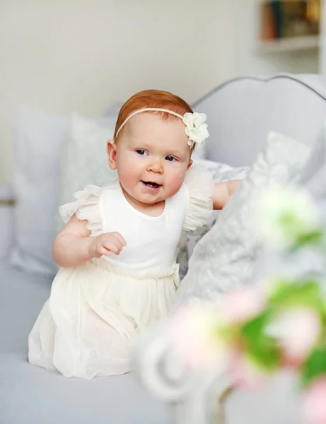 Porträtt av en söt liten flicka i en vit klänning i en hem ljus interiör. — Stockfoto