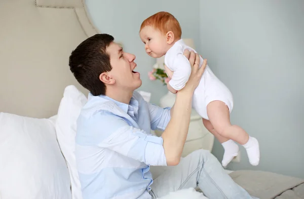 Un padre feliz jugando con un adorable bebé en el dormitorio — Foto de Stock
