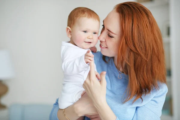 Mujer bonita sosteniendo a un bebé recién nacido sonriente en sus brazos — Foto de Stock