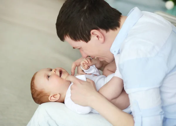 Un padre feliz jugando con un adorable bebé en el dormitorio — Foto de Stock