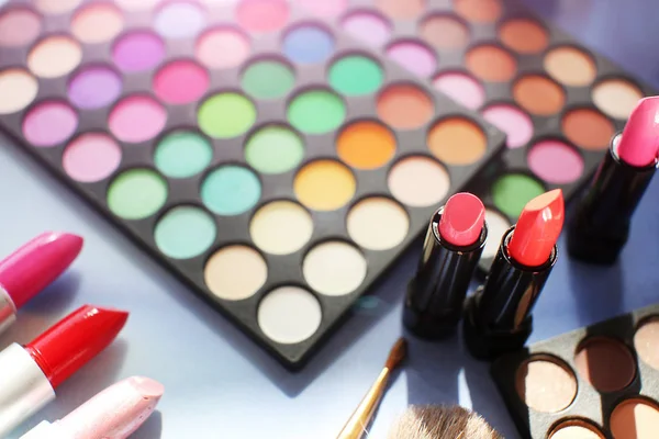 Professional make up set: eyeshadow palette, lipstick, make-up brushes and many cosmetics close up. Film and flare effect.