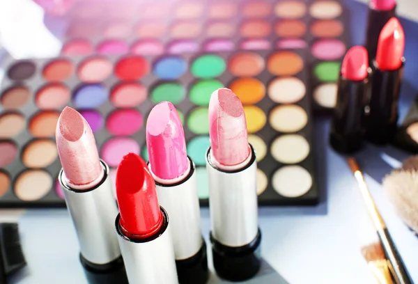 Professional make up set: eyeshadow palette, lipstick, make-up brushes and many cosmetics close up. Film and flare effect.