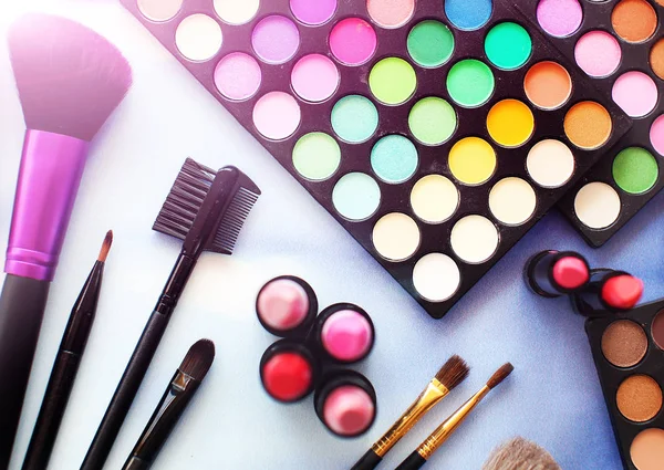 Professional make up set: eyeshadow palette, lipstick, make-up brushes and many cosmetics close up. Film and flare effect. Top view, flatlay