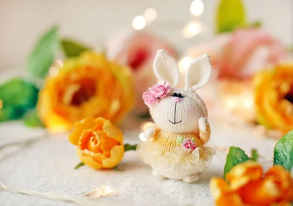 수 제 니트 토끼입니다. 꽃과 노란 드레스에서의 부활절 토끼 봄 구성 스톡 사진