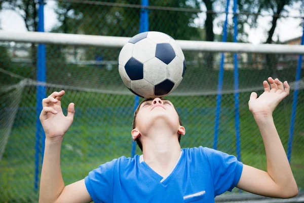Menino malabarismo uma bola de futebol — Fotografia de Stock