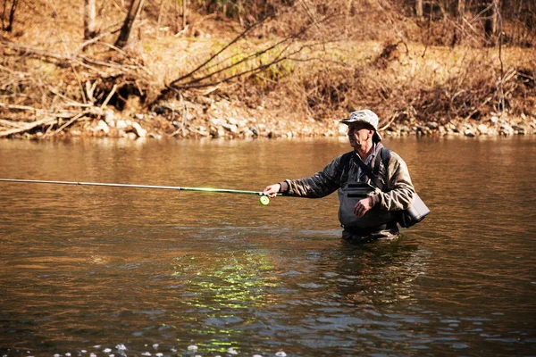 Fischer mittleren Alters fangen Äschen im Fluss — Stockfoto