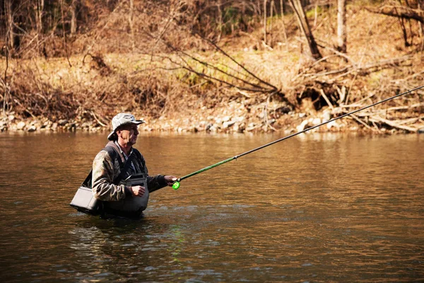 Pescatore di mezza età che cattura il temolo nel fiume — Foto Stock