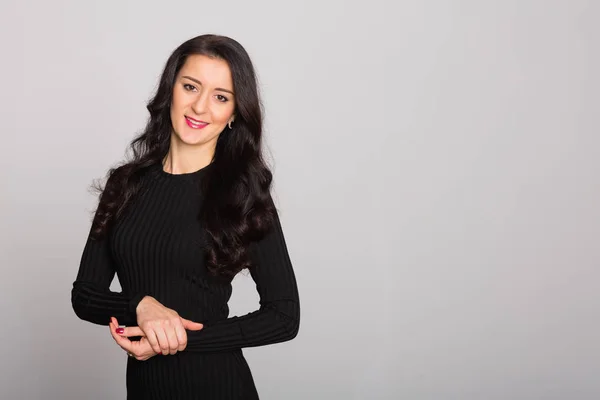 Menina encantadora com cabelo preto em um fundo de parede cinza — Fotografia de Stock