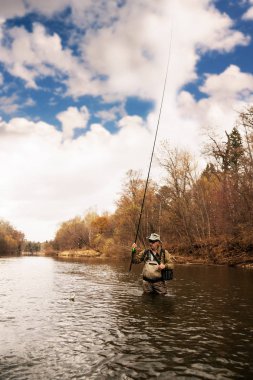 Balıkçı alabalık nehirde çeker. 
