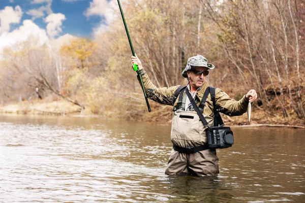 Pescador segurando um cinzento capturado no rio — Fotografia de Stock