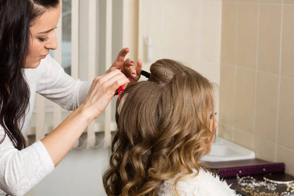 Hairdresser makes hair styling girl in a studio