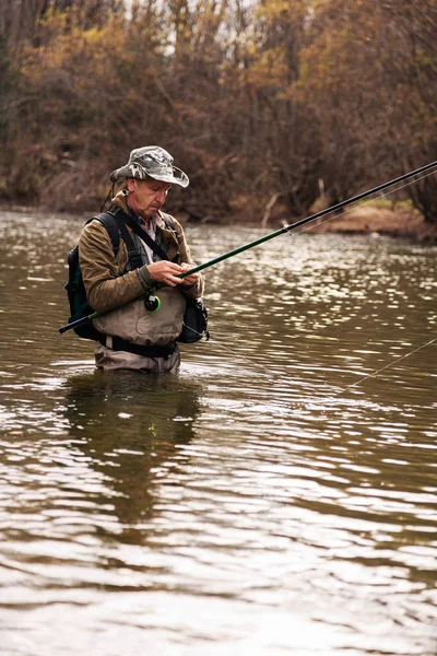 Rybář stojící v řece při lovu pstruhů — Stock fotografie