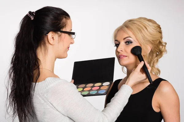 Maquillador haciendo maquillaje de una hermosa joven —  Fotos de Stock