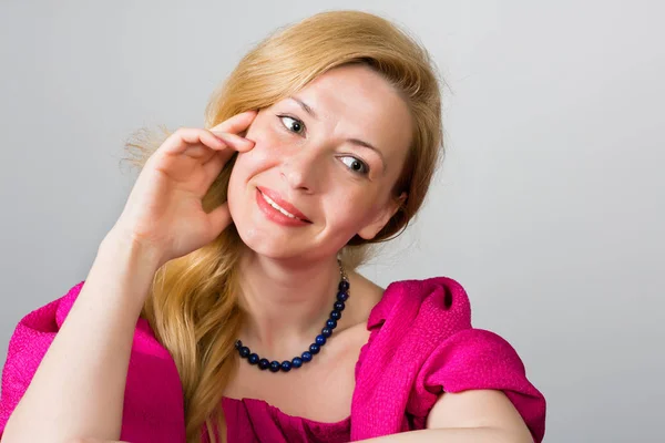 Bella donna con i capelli biondi su un grigio — Foto Stock