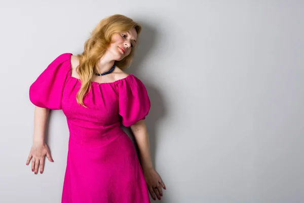 壁の近くのピンクのドレスで美しい女性 — ストック写真