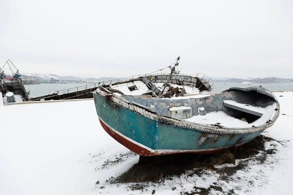 冬天的时候，那艘破了的旧救生艇躺在码头上 — 图库照片