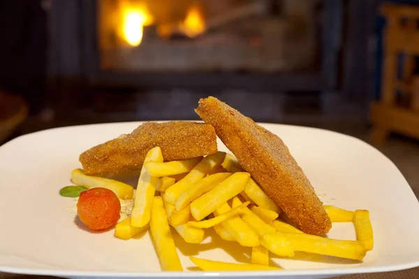 Detail of golden fried cheese with chips in front of a fireplace