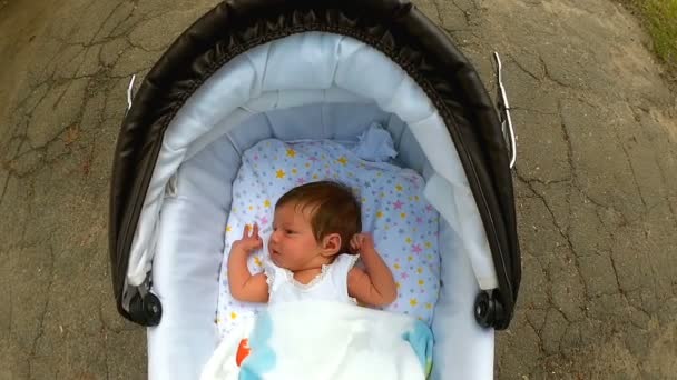 Baby liggend in de kinderwagen en glimlachen — Stockvideo