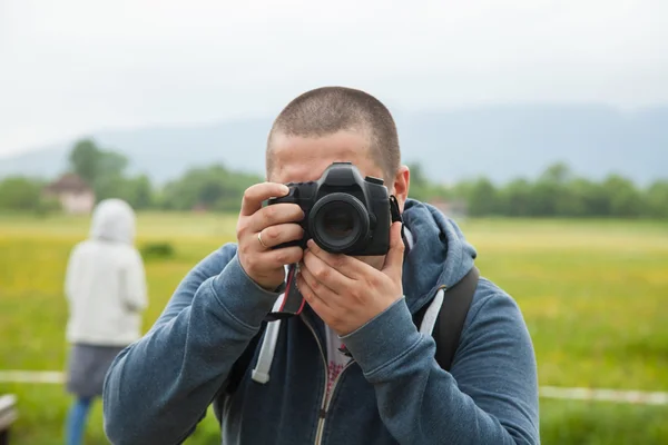 Homem segurando câmera e tirando fotos — Fotografia de Stock