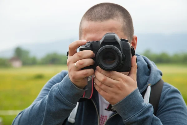 Чоловік тримає камеру і фотографує — стокове фото