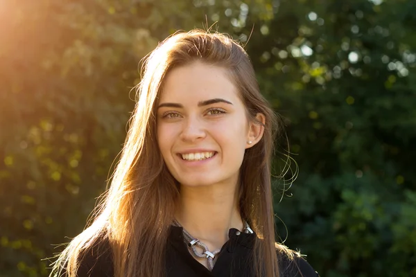 Jonge vrouw op de achtergrond van de bomen en zonlicht — Stockfoto