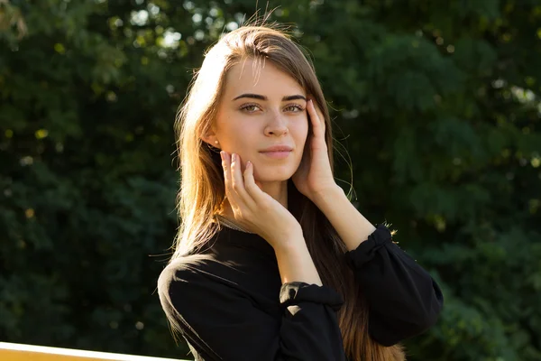 Jonge vrouw op de achtergrond van bomen — Stockfoto