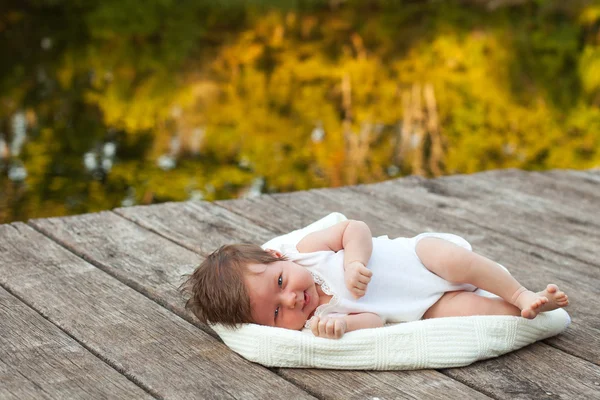 Bébé couché sur la couverture sur la jetée hext à la rivière — Photo
