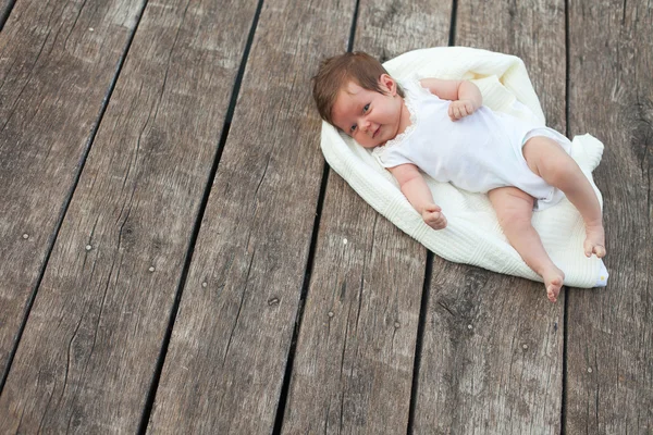 Baby lying on the blanket on the wooden floor — Stock Photo, Image