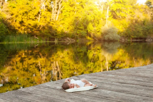 Baby lying on the blanket on pier hext to the river — Stock Photo, Image