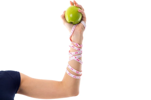 Womans hand with centimeter around it holding an apple — ストック写真